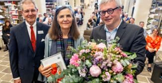 Dr. Wilhelm J. Koller, Vorstand der Hans und Helga Eckensberger Stiftung, Prof. Dr. Pamela Smith, Columbia University in the City of New York und Prof. Dr. Peter Burschel, Direktor der Herzog August Bibliothek Wolfenbüttel stehen vor Publikum in einer Halle